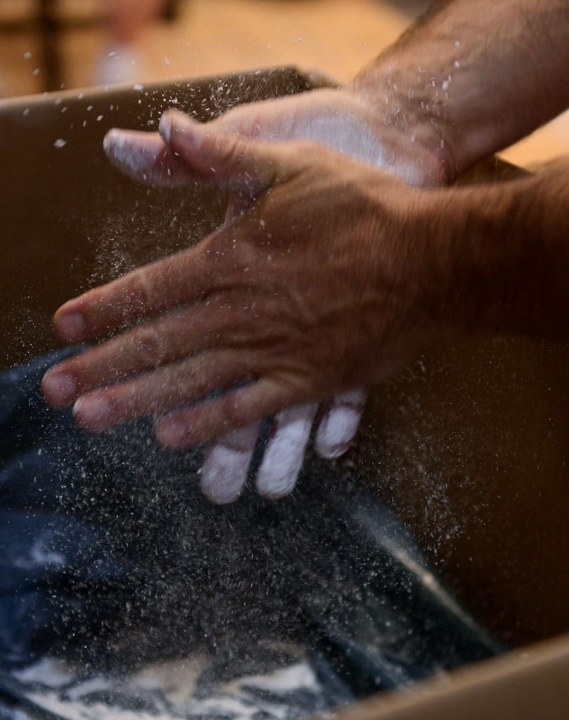 A power lifter chalks up his hands before his turn